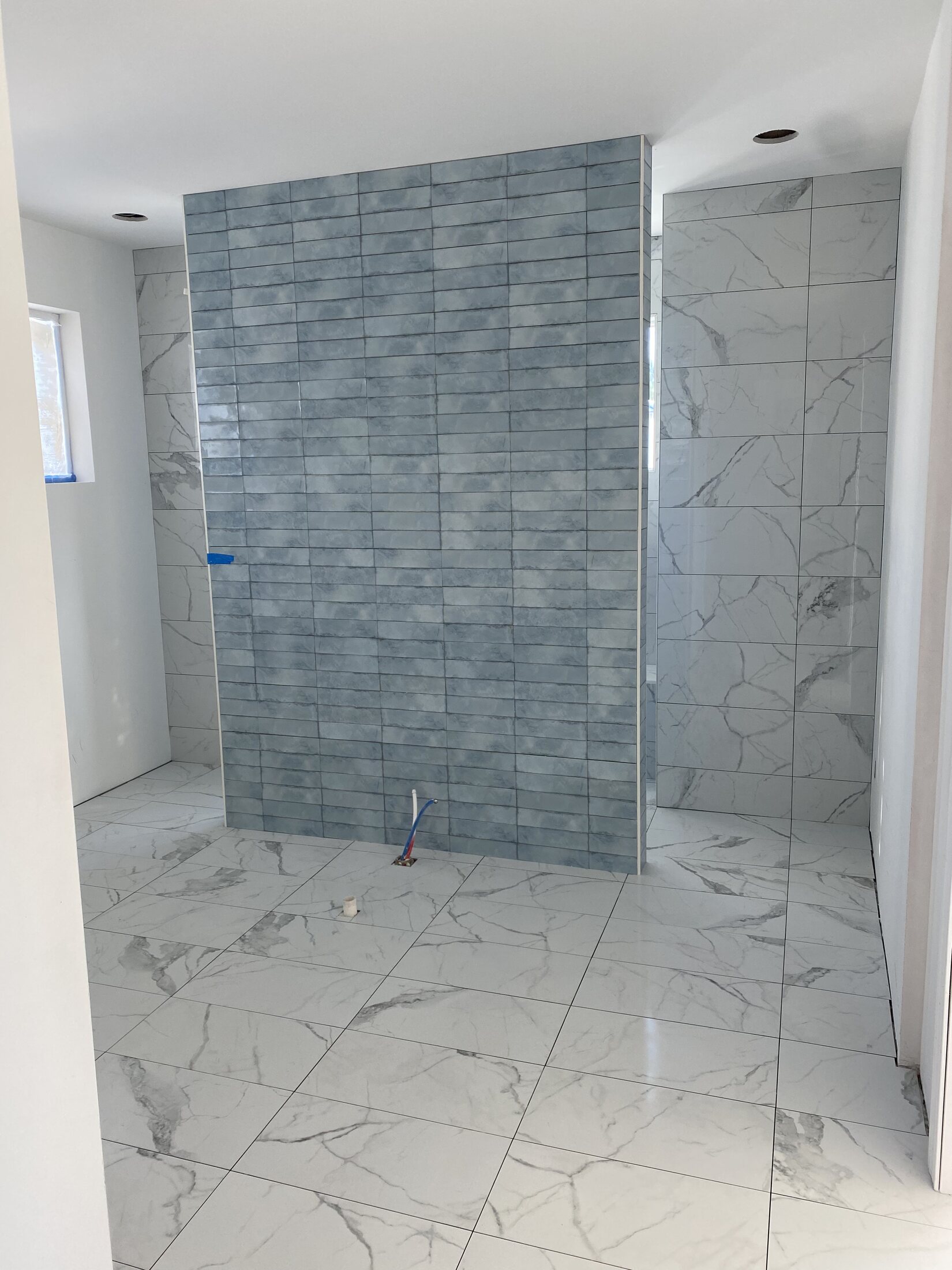 Large-format marble-look tile across a bathroom floor and walls