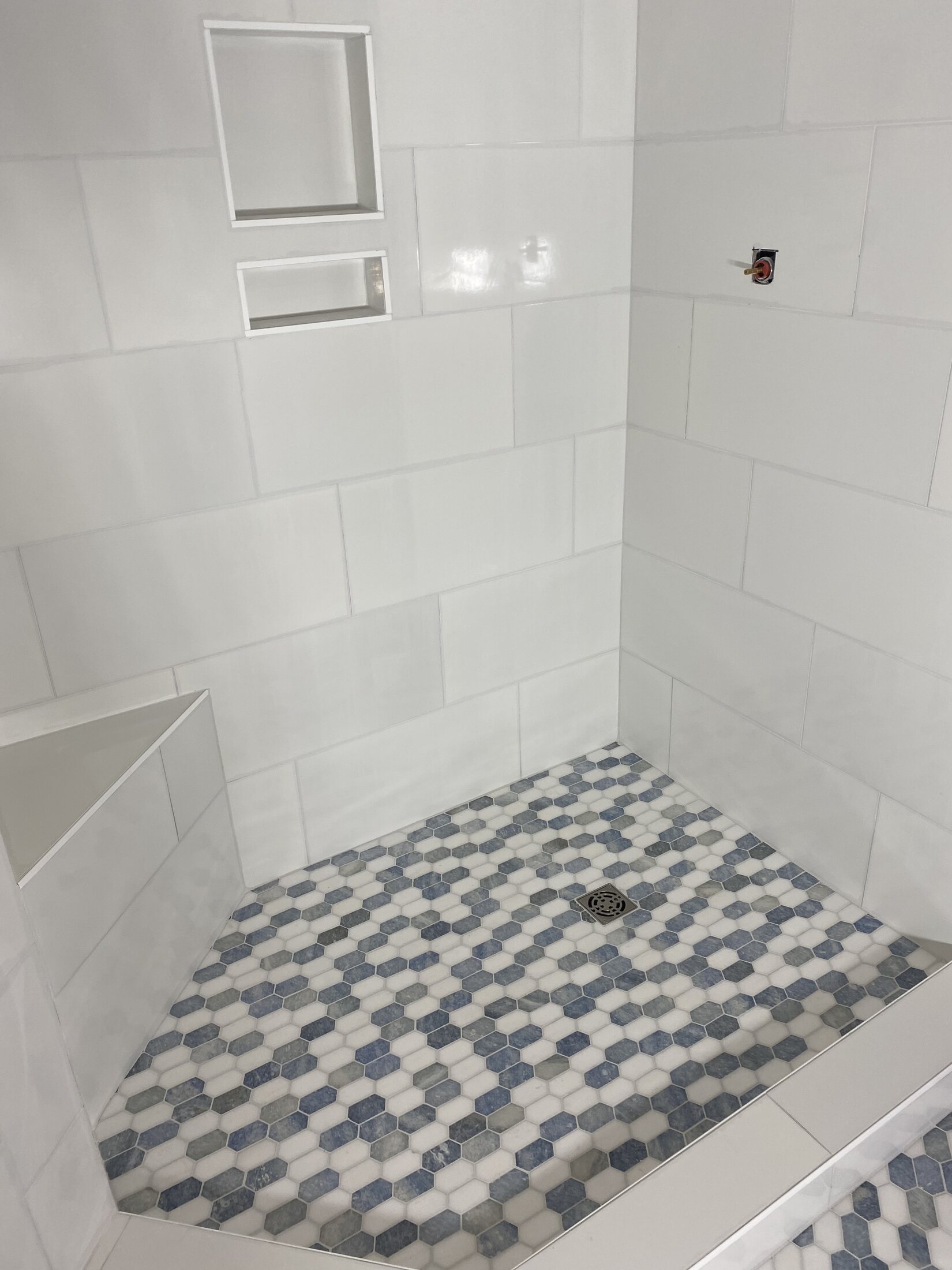 Walk-in shower with white wall tile and blue-gray mosaic floor
