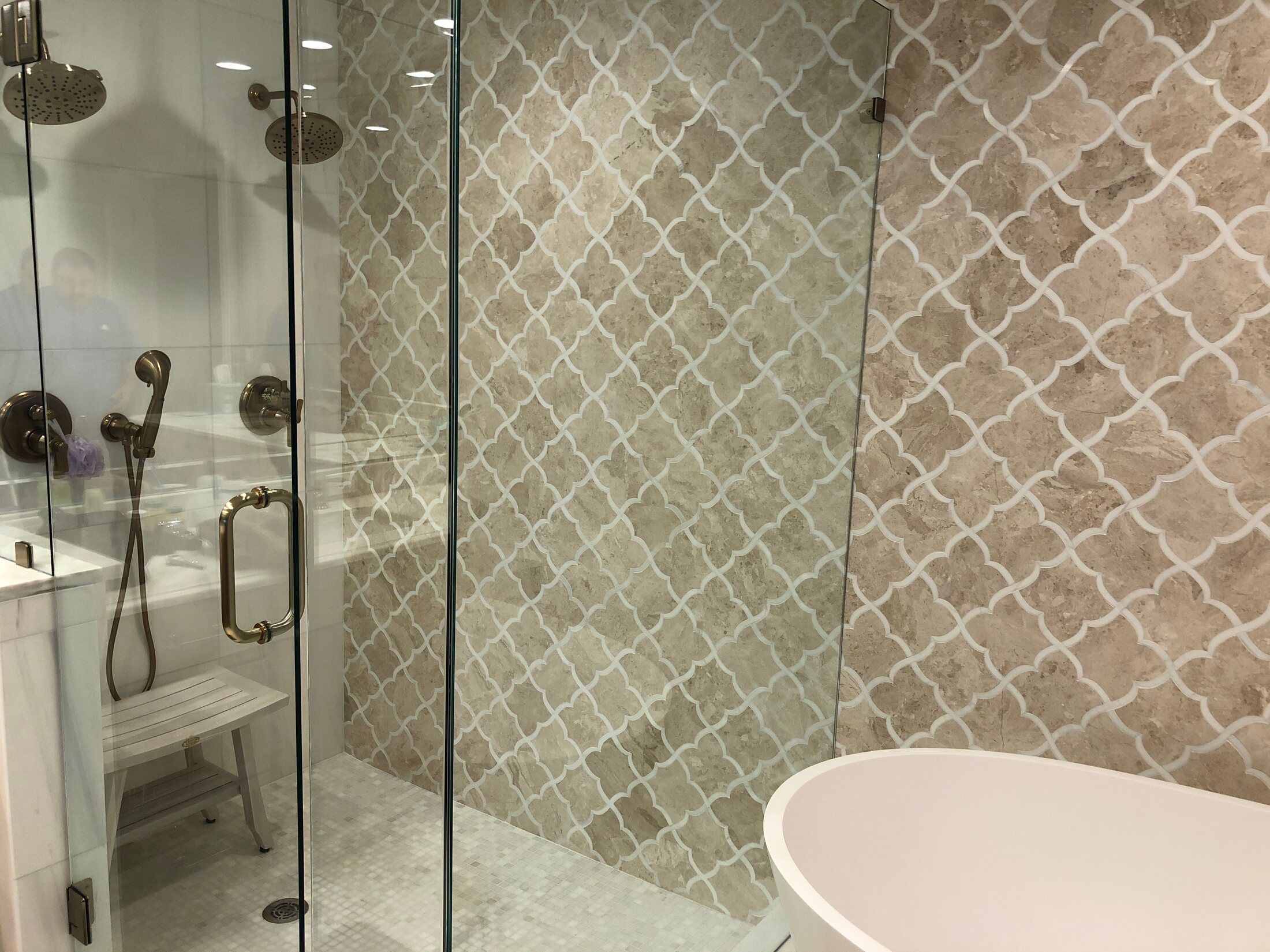 Custom tiled shower with glass enclosure and patterned stone wall